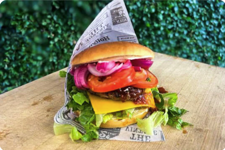 risen & Gaflen Signaturburger Pretzel-style burgerbolle med 160 g friskt hakket okse fra Himmerland, hemmelig BBQ-sauce, cheddar, chipotle, sprød romainesalat, tomat og hibiscus-syltede løg.